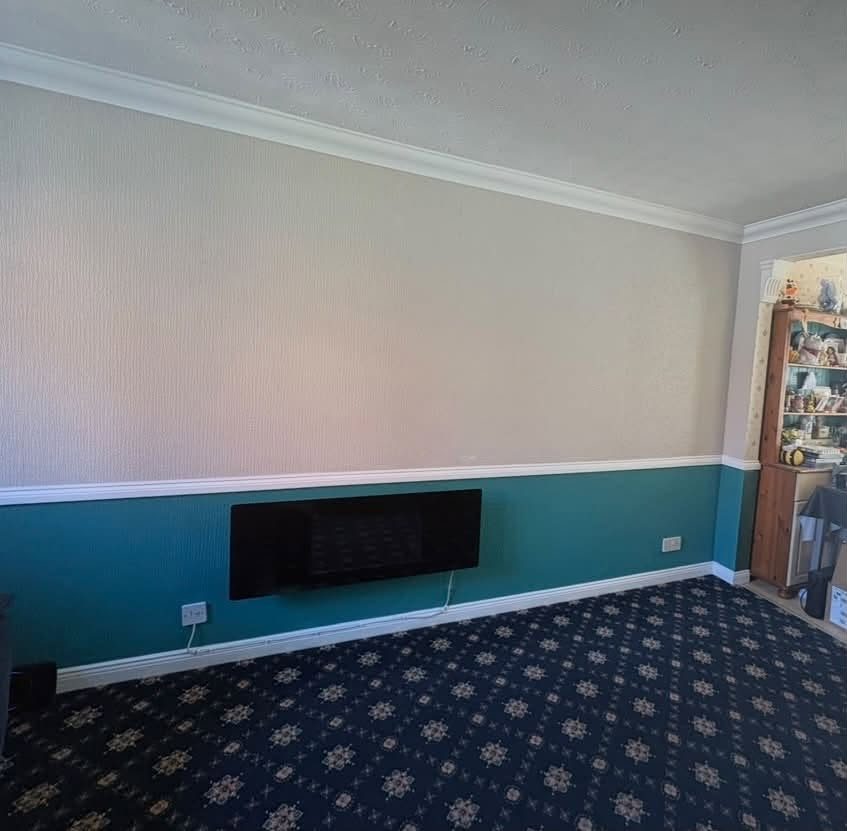 Living room with teal lower wall below a white dado rail and pale textured paper above
